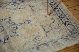 Distressed Oushak rug with aged ivory field, navy patterns, and meandering vine border.
