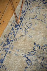 Distressed Oushak rug texture in dusty beige and navy, with knot head wear and foundation etching.