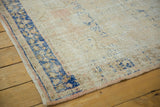 Distressed Oushak rug edge, showing worn ivory and apricot pile with navy border.