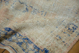 Detailed texture of distressed vintage Oushak rug, showing faded ivory, apricot, and navy blue.