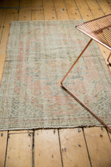 Faded pale pink, blue, and green floral vinery on a distressed vintage Oushak rug.