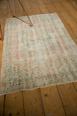 Distressed Oushak rug showing worn pile with faint foundation, secured end, and muted pastels.