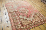 Blush, pale yellow, bronze reciprocating palmette motifs on a distressed Oushak rug border.