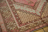 Blush reciprocating palmette motifs and lattice corner spandrels on this distressed Oushak rug.