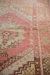 Distressed blush and beige Oushak rug with stepped geometric patterns and foundation wear.