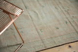 Distressed texture of a vintage Oushak rug, showing ivory and aqua hues with faint foundation.