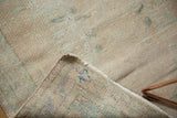 Oushak rug corner lifted, revealing worn pile, woven back, and blue painted number.