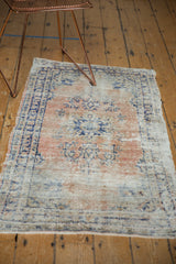 Distressed Oushak rug's faded apricot, beige, and navy blue floral patterns.