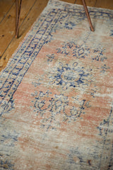 Distressed apricot and navy blue Oushak rug with areas of exposed foundation.