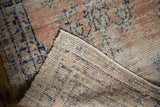 Corner detail: distressed apricot and navy pile, revealing the hand-knotted Oushak rug foundation.