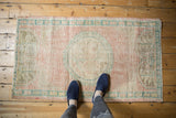 Vintage Distressed Oushak rug corner with pale pink field, deep ocean green border, even wear.