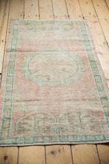 Distressed Oushak rug pile with pale pink and ocean green border detail.