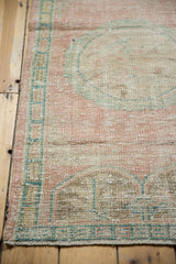 Distressed vintage Oushak rug texture, showing pale pink, ocean green, and faint foundation.