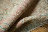 Distressed vintage Oushak rug pile texture with pale pink, ocean green, ivory hues and fringed edge.