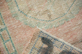 Distressed Oushak rug's worn pile texture with faint foundation, muted pink, green, and blue tones.
