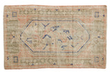 Distressed vintage Oushak rug with ivory elongated medallion, navy, pink, and sage green.