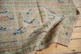 Distressed Oushak rug pile with even wear, showcasing ivory, navy, pink, and sage motifs.