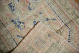 Distressed vintage Oushak rug corner revealing low pile, visible foundation, muted ivory, blue, pink.