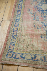 Distressed vintage Oushak rug's secured side edge, showing worn blush and blue pile.