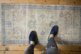Distressed vintage Turkish Oushak rug with ivory and dusty blue outwardly directed floral designs.