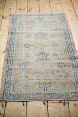 Distressed vintage Oushak rug showing worn texture, floral motifs, cobalt blue and pink tones.