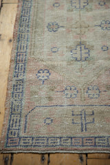 Textured distressed Oushak rug with soft beige pile, visible knot heads, and blue border.