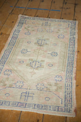 Distressed texture of a vintage Oushak rug with pale pink, ivory, and dusty blue geometric motifs.