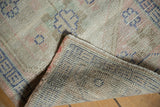 Texture of a distressed Oushak rug, showing worn ivory pile and hand-knotted foundation.
