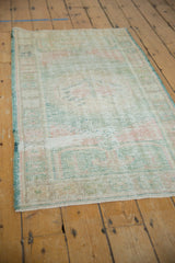 Distressed Oushak rug texture with even wear, pale rose, and ocean green secured side.