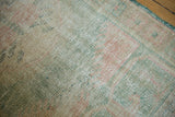 Distressed Oushak rug pile shows even wear, ocean green, pale rose tones.