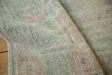 Distressed Oushak runner pile, showing worn knot heads and muted green, rose, ivory tones.