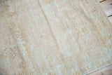 Distressed Oushak rug's textured pile in soft beige and sand with visible foundation etching.