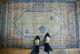 Distressed Oushak rug with ivory field, dusty blue, and pale pink Arts and Crafts pattern.