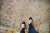 Distressed Oushak rug featuring blush, ivory, pale blue stepped corner spandrels and borders.