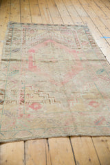Distressed vintage Oushak rug with muted blush central medallion and ivory field.