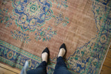 Distressed vintage Oushak carpet showcasing worn dusty rose pile with blue and mint florals.