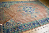 Distressed dusty rose field with cobalt blue palmette border on a vintage Oushak rug.