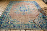 Distressed Oushak rug corner, worn dusty rose field, cobalt blue palmette border.