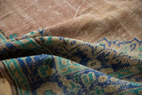 Textured fold of distressed Oushak rug with faded rose and vibrant blue palmette border.