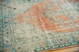 Distressed Oushak rug, terra cotta field with visible knot heads, sky blue vinery, and ivory border.