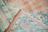 Distressed Oushak rug corner detail, revealing terra cotta, ivory, blue, and worn pile.