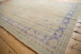 Distressed Oushak rug border pattern with faded royal blue, mint green, and worn pile.
