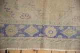 Distressed Oushak rug edge showing ivory fringe and a faded royal blue, mint green border.