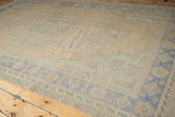Distressed Oushak carpet, worn low pile, faded blue floral motifs on an ivory field.