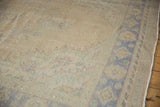Distressed vintage Oushak carpet pile showing soft beige, faded blue, and green border motifs.