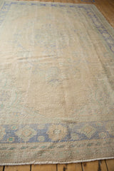 Distressed pile texture of a vintage Oushak rug, featuring faded beige, blue, and mint patterns.