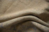 Distressed Oushak rug pile texture with visible knot heads, revealing muted beige and faded green.