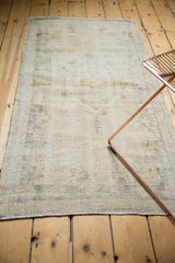 Distressed vintage Oushak rug texture with muted ivory, pale brown, and charcoal bronze.
