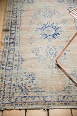 Distressed vintage Oushak runner with softened navy blue patterns on a pale blush field.