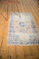 Distressed pale blush field, navy blue border, and secured end of a vintage Oushak rug.